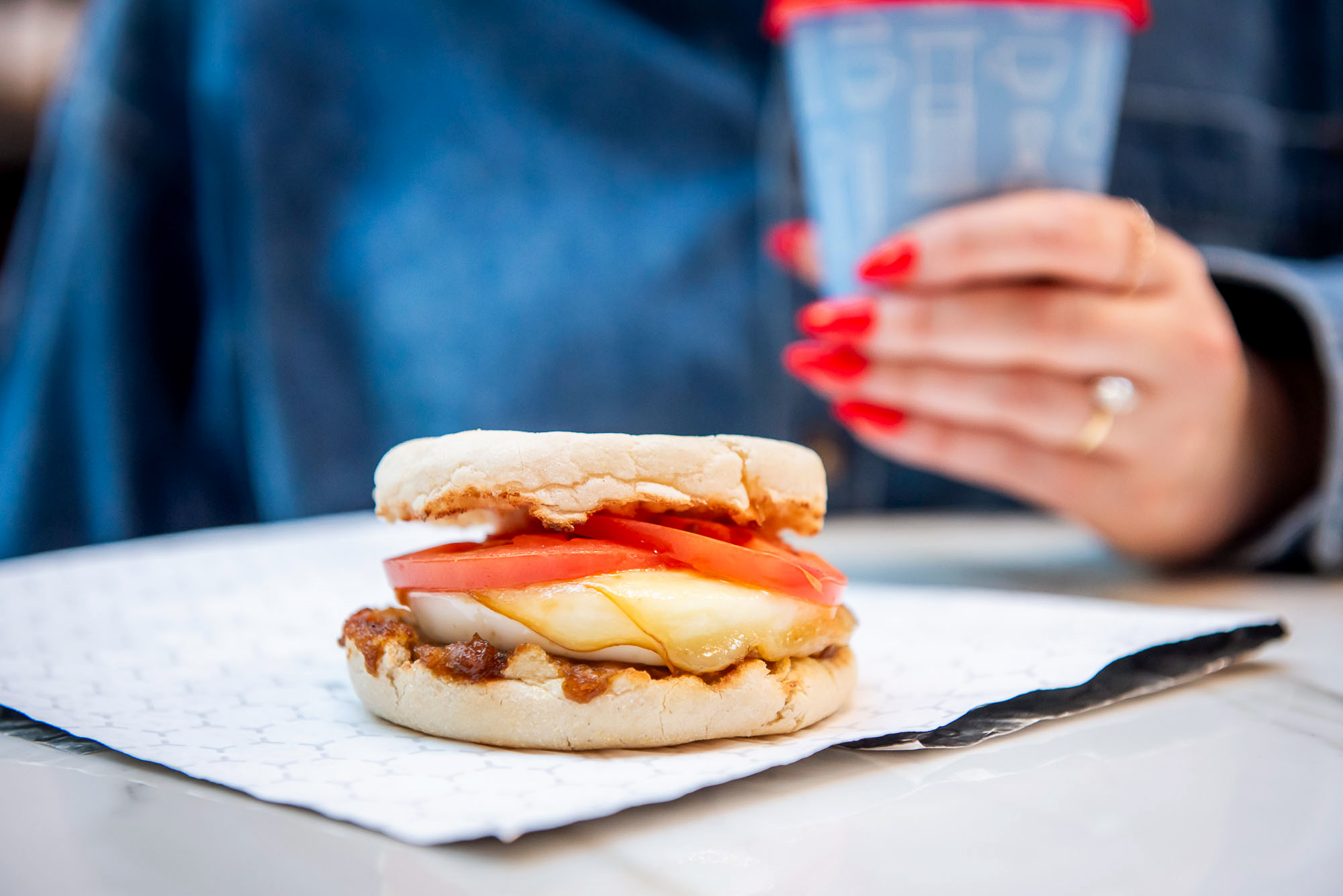cross bar breakfast sandwich with hand holding coffee
