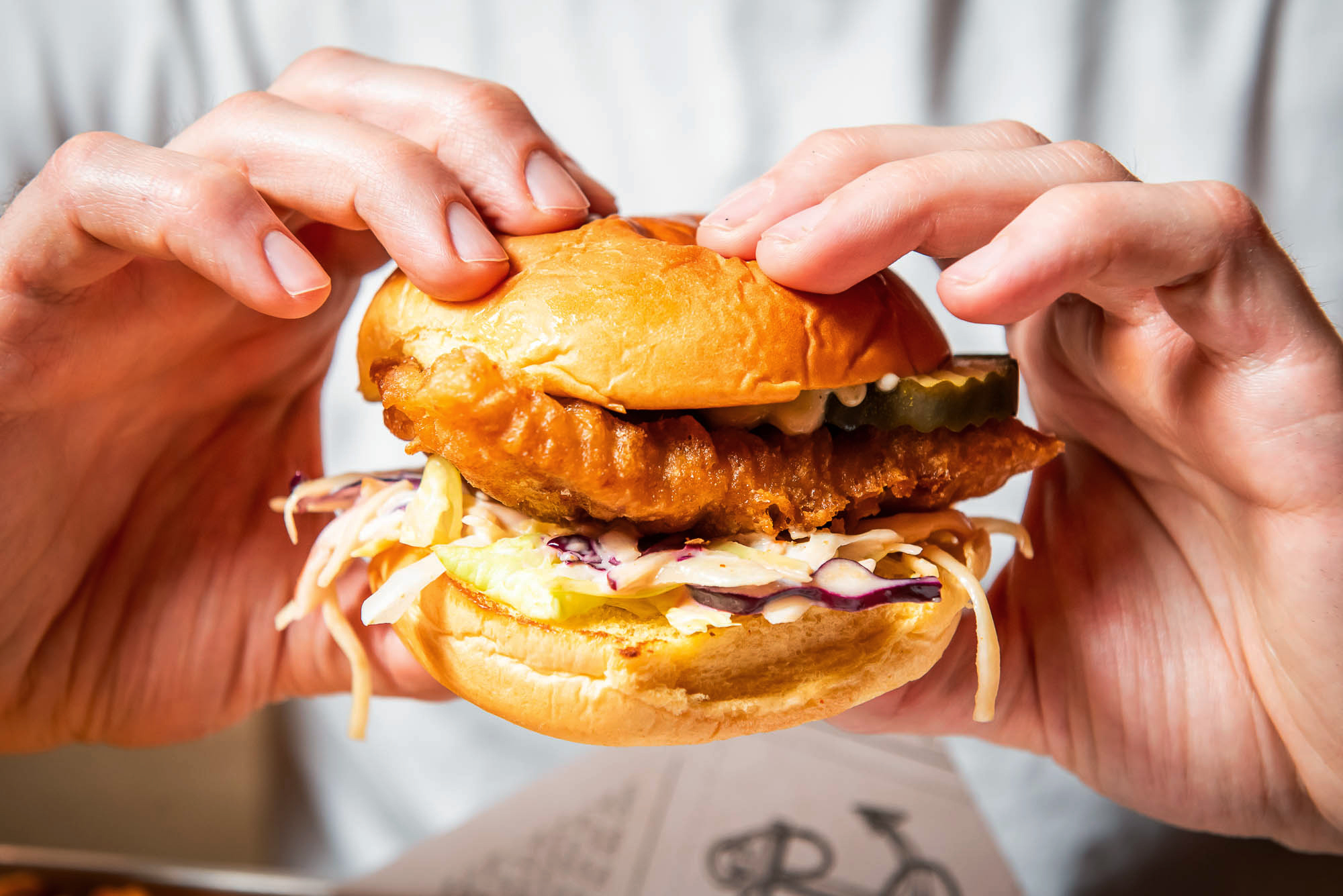 two hands hold a fish burger