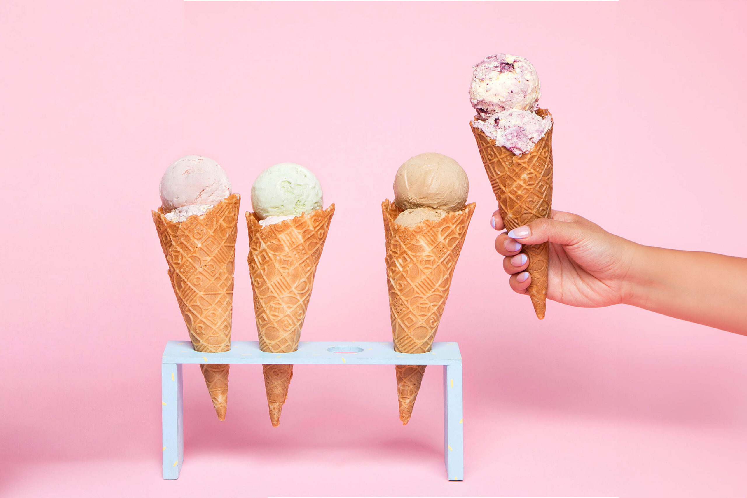 hand grabs icecreame cone on pink background