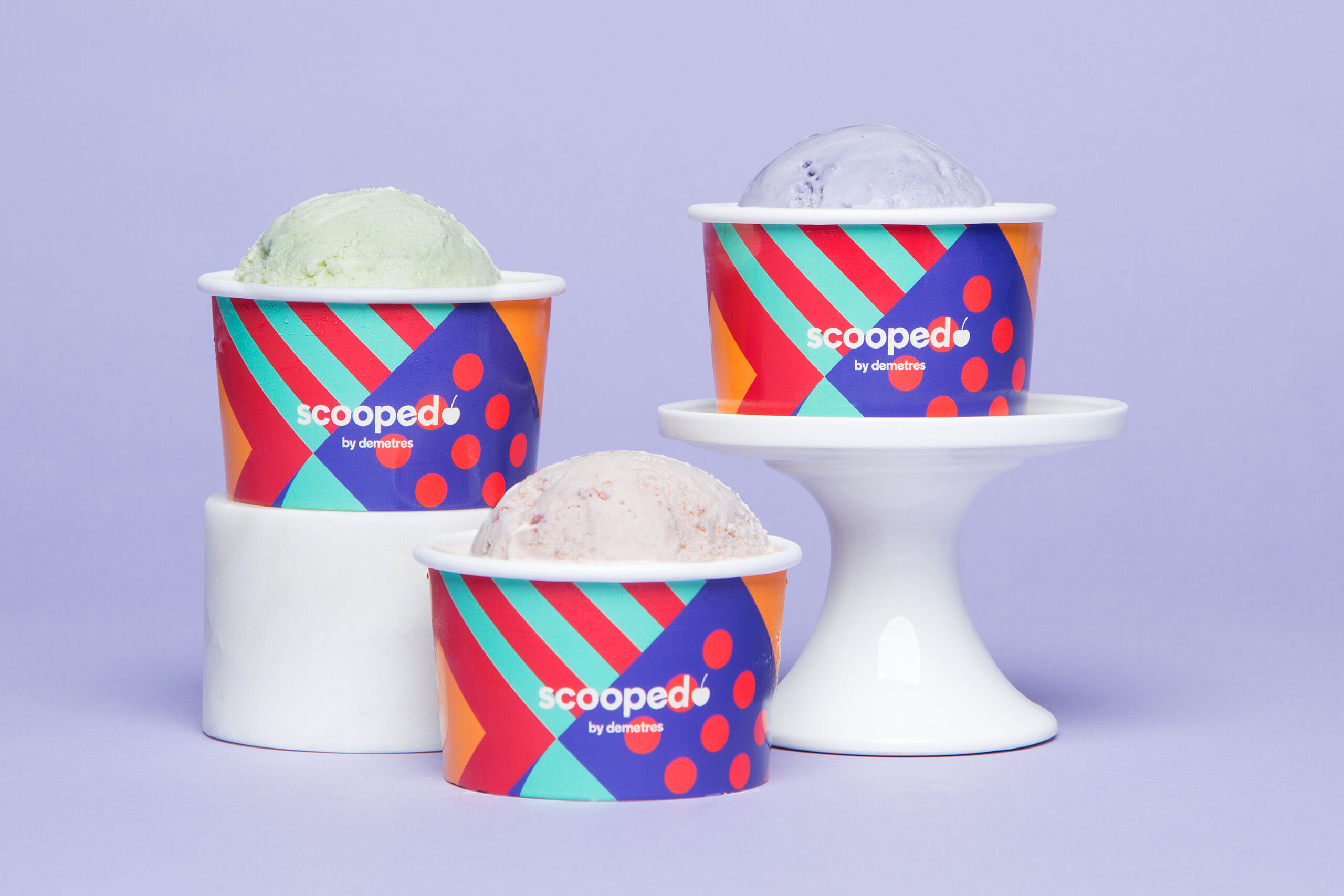 three cups of icecream in front of a purple background